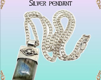 Puede incluir: Un collar de cadena de plata con un colgante de plata con una piedra preciosa de labradorita. El colgante tiene un diseño detallado con un pequeño patrón en forma de ojo. El texto "Beautiful Labradorite Silver Pendant" se muestra encima de la imagen.