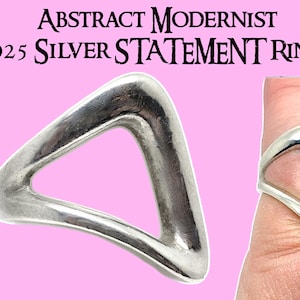 Könnte beinhalten: Ein silberner Statement-Ring mit abstraktem, modernistischem Design. Der Ring ist aus 925er Sterlingsilber gefertigt und hat eine dreieckige Form mit einem Ausschnitt in der Mitte.