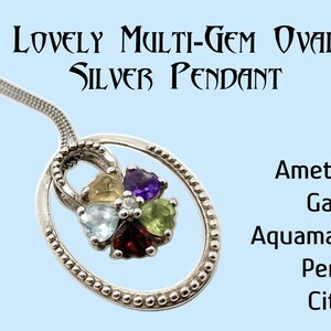 May include: A silver oval pendant necklace with a cluster of five heart-shaped gemstones. The stones are amethyst, garnet, aquamarine, peridot, and citrine.
