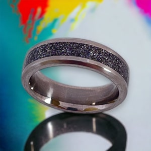 Könnte beinhalten: Nahaufnahme eines silbernen Rings mit einem dunklen, strukturierten Mittelband. Der Ring besteht aus einem metallischen Material und hat eine glatte, polierte Oberfläche. Der Ring ist ein Schmuckstück.