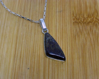May include: A silver chain necklace with a pendant featuring a dark brown, irregularly shaped stone.