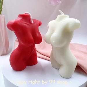 May include: Two decorative candles shaped like a human torso. One candle is red and the other is white.