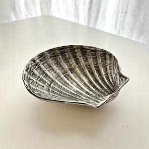 Może przedstawiać: Zestaw trzech ceramicznych misek w różnych rozmiarach. Miski są białe z nakrapianym, teksturowanym wykończeniem i lekko rozszerzonym brzegiem. Największa miska ma średnicę około 20 cm.
