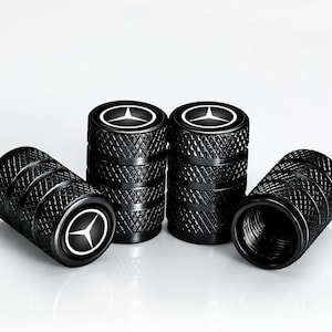 May include: Black tyre valve stem caps with a diamond pattern and a white Mercedes-Benz logo. The caps are cylindrical and have a threaded interior for secure attachment to the tyre valve stem.