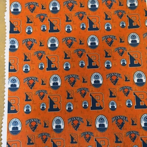 May include: Orange fabric with a repeating pattern of the letter "B", the word "BUCKNELL", and a university emblem in navy blue and white. The fabric is likely for crafting or apparel.