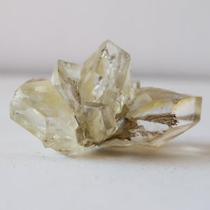 May include: A cluster of clear, translucent, yellow-toned crystals with a slightly rough texture.