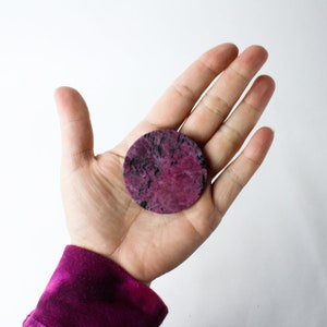 May include: A round, pink and black, polished stone with a smooth surface.