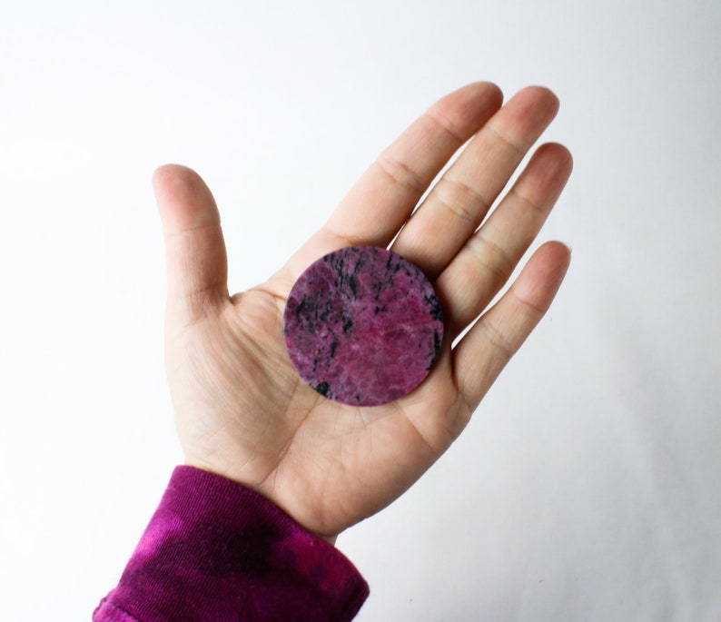May include: A round, pink and black, polished stone with a smooth surface.
