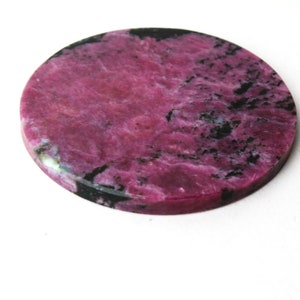 May include: Round pink and black gemstone cabochon with a marbled pattern.
