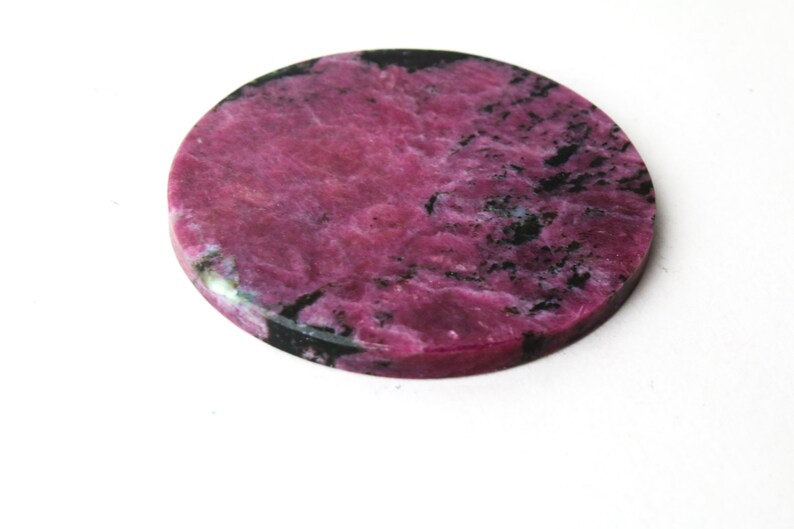 May include: Round pink and black gemstone cabochon with a marbled pattern.