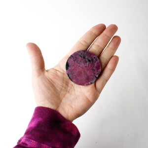 May include: A round, pink and black, polished stone coaster.