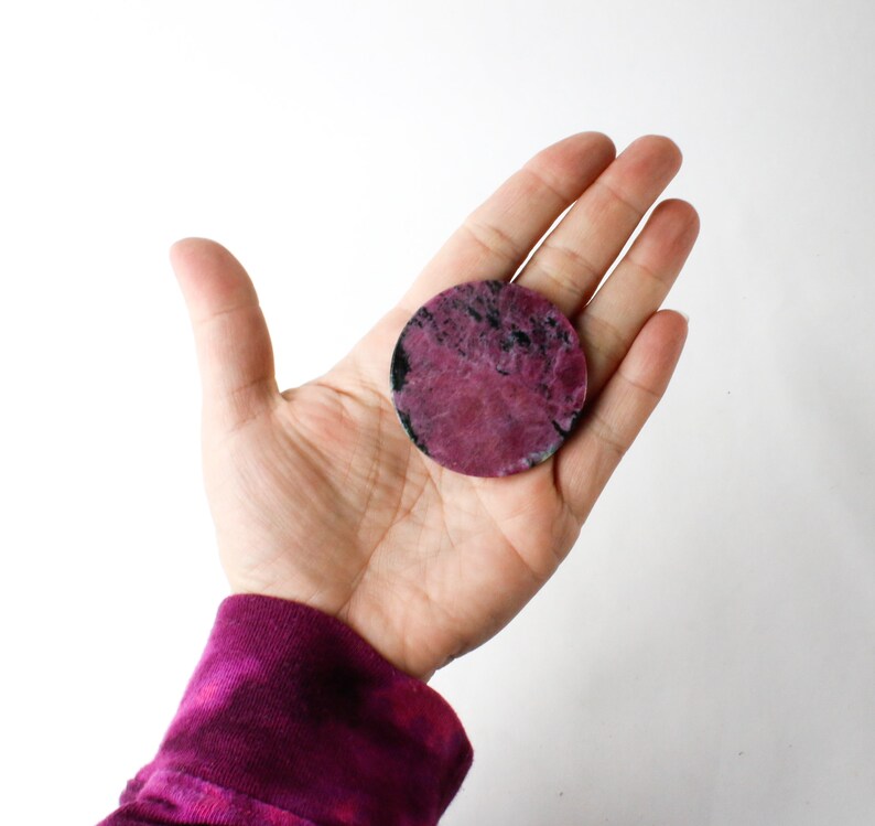 May include: A round, pink and black, polished stone coaster.