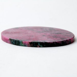 May include: Round pink and green stone coaster with a smooth surface.