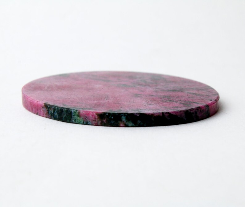 May include: Round pink and green stone coaster with a smooth surface.