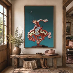 May include: A rectangular wall art print featuring a vintage-style neon sign of a cowboy riding a bucking horse. The sign displays the word WELCOME in illuminated lettering against a dark teal background with a small white crescent moon.