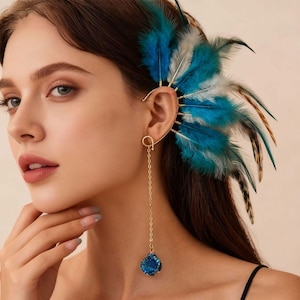 May include: A gold-coloured ear cuff with a dangling blue gemstone and chain. The ear cuff features a design of blue, white, and brown feathers. The jewelry is an elegant accessory.