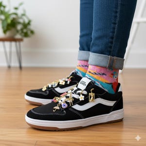 Puede incluir: Zapatillas Vans negras con rayas laterales blancas y suela blanca. Las zapatillas est&aacute;n adornadas con abalorios decorativos en oro, blanco y colores pastel. Se usan con vaqueros azules doblados y calcetines estampados coloridos.