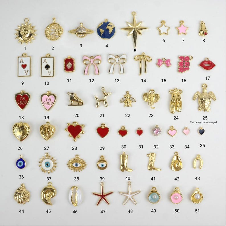 Puede incluir: Una colecci&oacute;n de colgantes dorados con diversas formas, incluyendo estrellas, corazones, lazos y s&iacute;mbolos de naipes. Algunos colgantes presentan detalles de esmalte en colores como rojo, rosa y azul. Los colgantes son para la creaci&oacute;n de joyas.