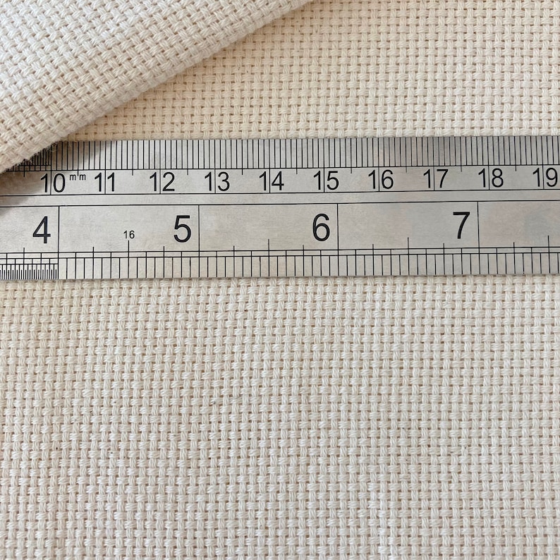 Puede incluir: Primer plano de una tela blanca con una regla que mide 17,8 cm. La tela tiene un patr&oacute;n de cuadr&iacute;cula.