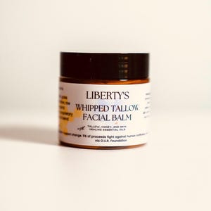 May include: A jar of Liberty's Whipped Tallow Facial Balm. The jar has a dark brown lid and a white label with black text. The label includes the product name and ingredients: tallow, honey, and skin healing essential oils.