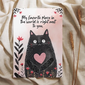 May include: A greeting card featuring a black cat with a pink heart, surrounded by flowers. The text reads, "My favorite place in the world is right next to you." The background is a soft pink.