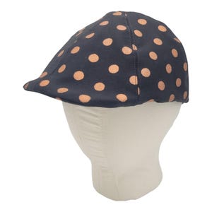 May include: A navy blue and peach polka dot newsboy cap.