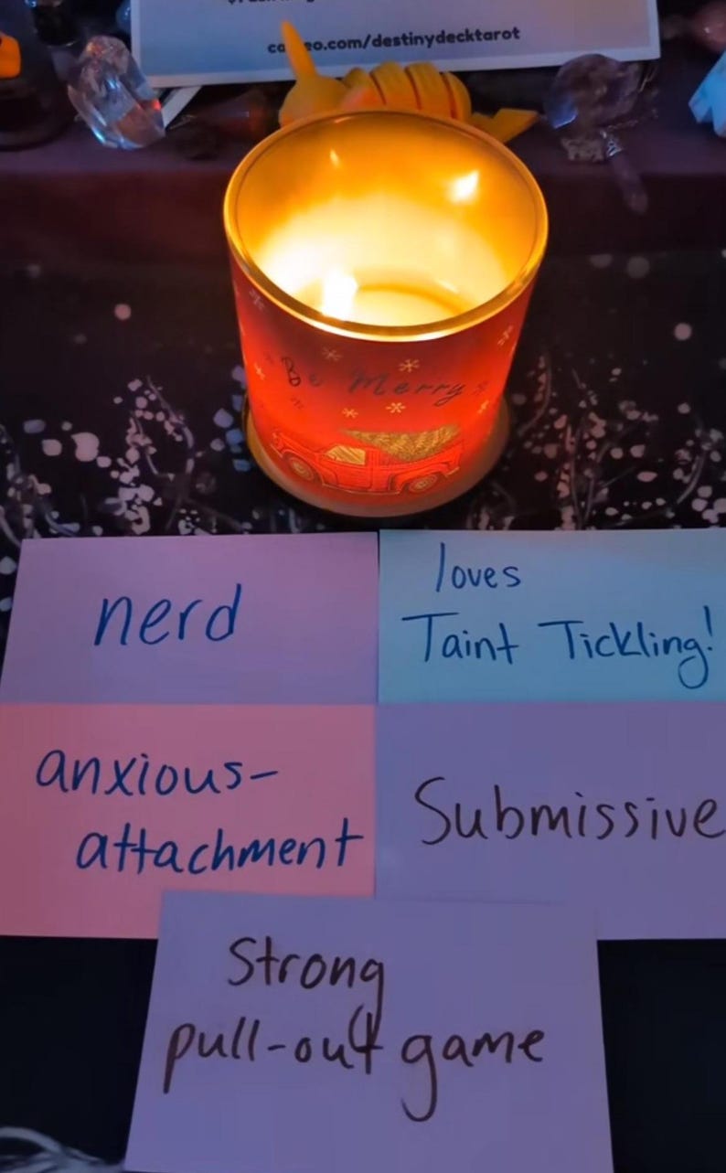 May include: Four pink, blue, and purple sticky notes with handwritten text. The notes say "nerd", "loves taint tickling", "anxious-attachment", and "submissive". A fifth sticky note says "strong pull-out game". A lit candle with a red and white design is in the background.