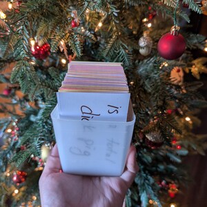 May include: A white plastic container filled with a stack of colorful index cards. The container has handwritten text on it that says "Happy &  Did I?"