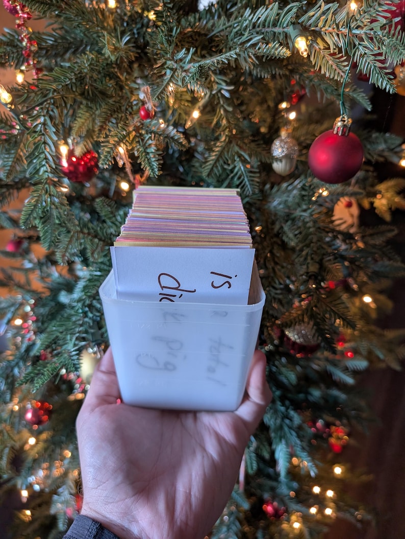 May include: A white plastic container filled with a stack of colorful index cards. The container has handwritten text on it that says "Happy &  Did I?"