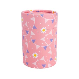 Puede incluir: Contenedor cil&iacute;ndrico rosa con un patr&oacute;n de margaritas blancas y banderines morados y rosas.