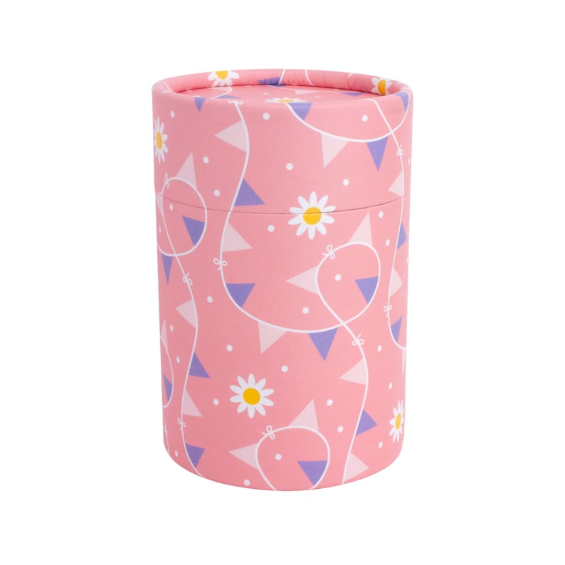 Puede incluir: Contenedor cil&iacute;ndrico rosa con un patr&oacute;n de margaritas blancas y banderines morados y rosas.
