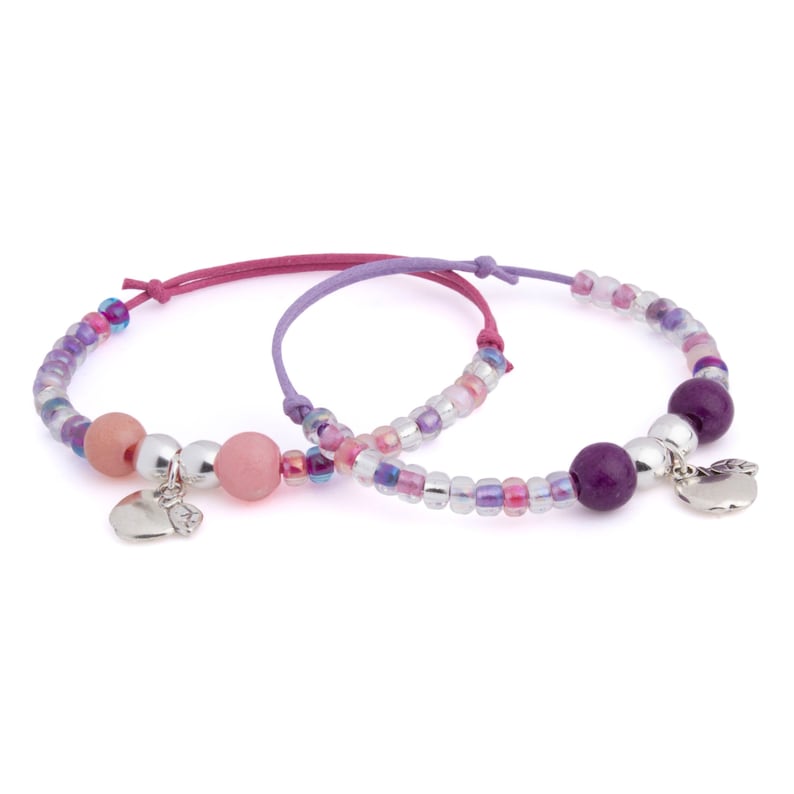 Puede incluir: Dos pulseras de cuentas con dijes de coraz&oacute;n plateados. Una pulsera es rosa y morada con un dije de coraz&oacute;n rosa. La otra pulsera es morada y blanca con un dije de coraz&oacute;n plateado.