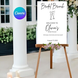 Könnte beinhalten: Ein weißes Schild auf einer Holzstaffelei mit dem Text "Bridal Brunch" und "Willkommen bei Olivia's Bridal Shower". Das Schild enthält das Datum 17. August 2025 und ist mit Blumen geschmückt. Das Canva-Logo ist sichtbar.