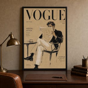 May include: A framed vintage Vogue magazine cover print from May 15th, 1951, featuring a black ink illustration of a person sitting in a chair reading a newspaper at a small table with a coffee cup, set against a tan background with black text.