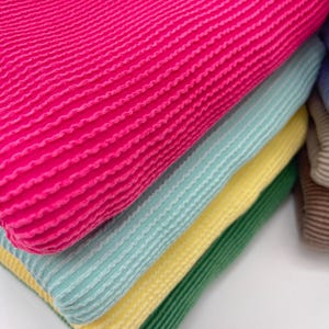 A close-up of the middle fabrics in the left stack, showing the ribbed texture of the fuchsia, aqua, and yellow fabrics.