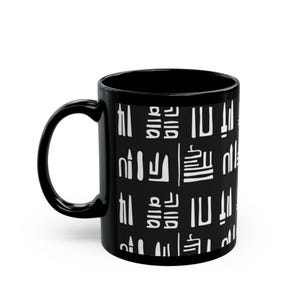 May include: Black ceramic coffee mug with a white abstract pattern. The mug has a curved handle and a cylindrical shape. The white pattern is composed of various geometric shapes and symbols, creating a modern design.