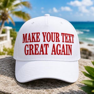 K&ouml;nnte beinhalten: Eine wei&szlig;e Baseballkappe mit dem rot gestickten Text "MAKE YOUR TEXT GREAT AGAIN". Die Kappe wird vor dem Hintergrund eines Strandes mit Palmen und Meer gezeigt.