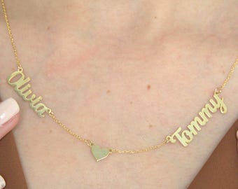 May include: Gold necklace with two names, "Olivia" and "Tommy", separated by a small heart charm.