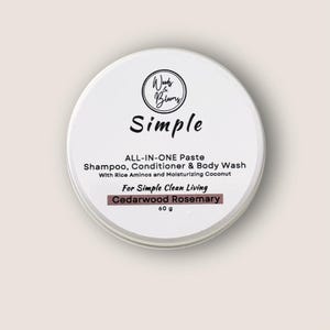 May include: A white tin container with a black label that reads "Winks & Blooms Simple ALL-IN-ONE Paste Shampoo, Conditioner & Body Wash With Rice Aminos and Moisturizing Coconut For Simple Clean Living Cedarwood Rosemary 60 g"