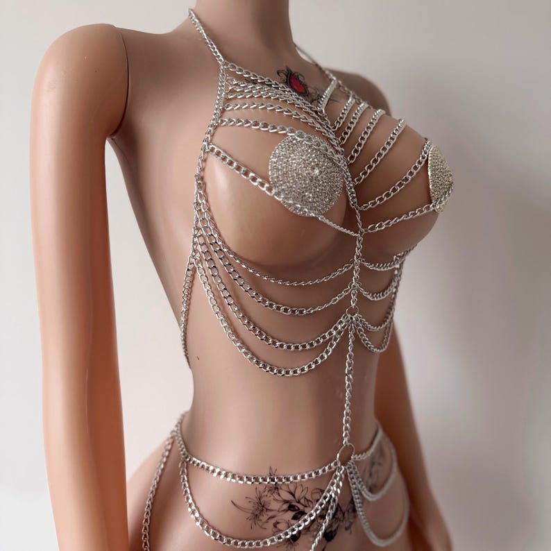 May include: Silver chain body jewelry with rhinestones. The chain is layered and has a delicate design.