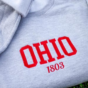 May include: Gray sweatshirt with red embroidered text that says "OHIO 1803".