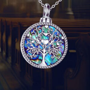 May include: A silver necklace with a round pendant featuring a silver tree of life design with abalone shell inlay and silver hearts.
