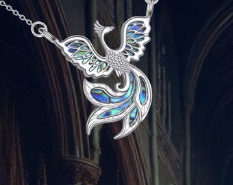 Pode incluir: Colar de prata com um pingente de fênix de madrepérola azul e verde. A fênix é uma ave mítica que simboliza o renascimento e a renovação.