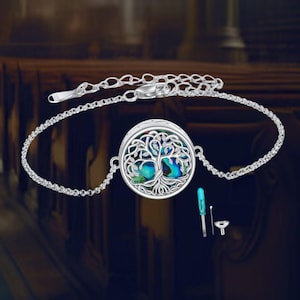 May include: A silver chain bracelet with a round pendant featuring a tree of life design. The pendant has a blue and green abalone shell inlay. The bracelet comes with a small screwdriver and a funnel.
