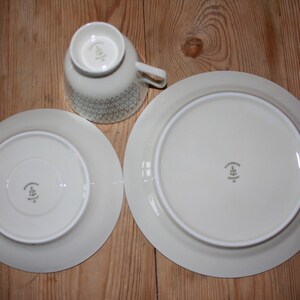 May include: A set of three ceramic mugs with a speckled, matte finish. The mugs are in shades of cream, light gray, and dark gray. Each mug has a simple, minimalist design and a rounded handle.