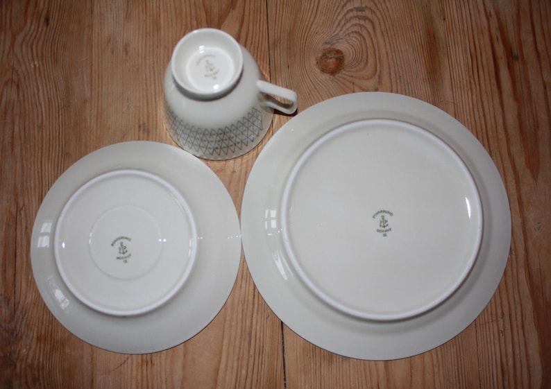 May include: A set of three ceramic mugs with a speckled, matte finish. The mugs are in shades of cream, light gray, and dark gray. Each mug has a simple, minimalist design and a rounded handle.