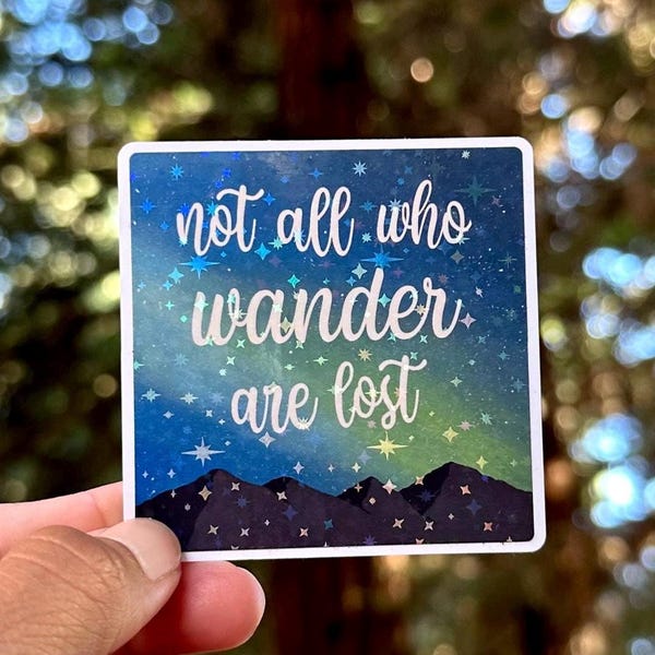May include: A blue and green iridescent sticker with a mountain range silhouette and the text "Not all who wander are lost" in white.