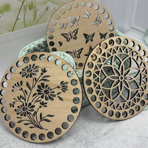 以下が含まれることがあります： 装飾的な切り抜きデザインの木製バスケットベース3つ。1つは蝶、もう1つは花の模様、3つ目は幾何学模様です。各ベースには周囲に等間隔に配置された一連の穴があり、明るい色の木材で作られています。