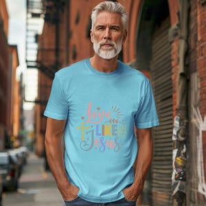 May include: A light blue t-shirt with a colorful graphic that says "Love Like Jesus".