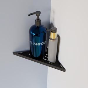 Puede incluir: Un estante de esquina negro con dos botellas de jabón líquido. La botella de la izquierda es azul y dice "SHAMPOO" en la parte delantera. La botella de la derecha es transparente con una tapa dorada.